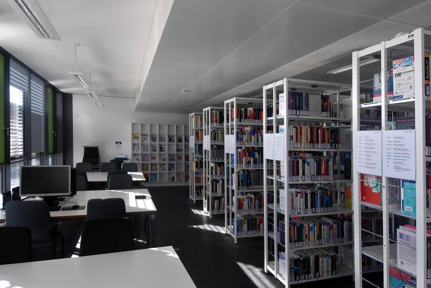 Blick in die Teilbibliothek am Sanderheinrichsleitenweg; links Tische zum Arbeiten, rechts Reihen von Regalen mit Büchern