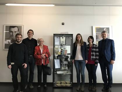 Von der Stiftung ausgezeichnete Studierende zusammen mit Frau Maria Fischer-Flach und Dekan Prof. Peter Braun vor einer Vitrine