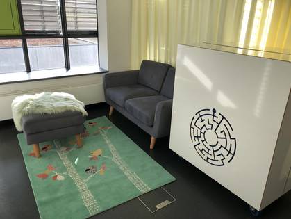 Der Ruhebereich des Eltern-Kind-Zimmers mit Couch, KidsBox, Teppich und Trenn-Vorhang